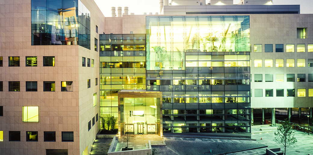 MIT Building 46, a modern glass and stone building, lit up at dusk