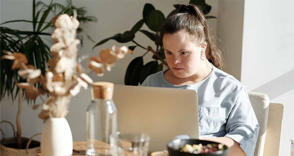 a woman with down syndrome works on a laptop